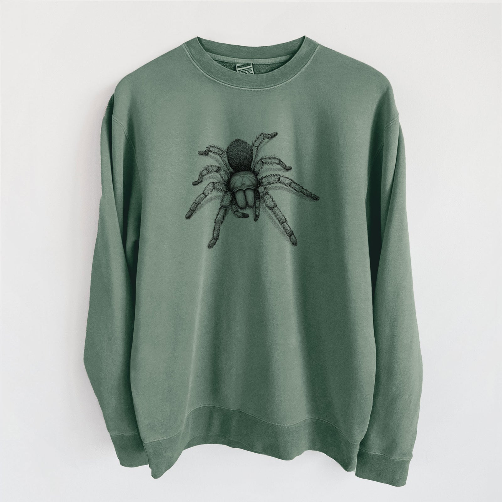 Alpine green pigment dyed crewneck sweatshirt laid flat, printed with a detailed black ink illustration of a desert blonde tarantula.