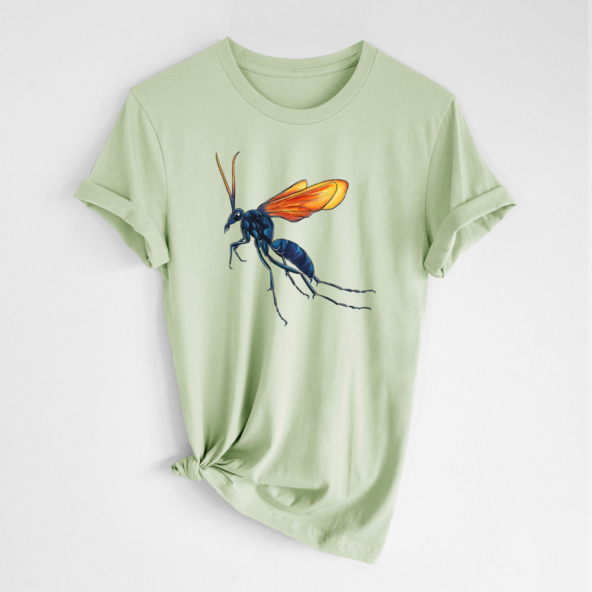 Spring green lightweight cotton t-shirt laid flat with the sleeves rolled, printed with a full-color illustration of a tarantula hawk wasp with a blue body and orange wings.