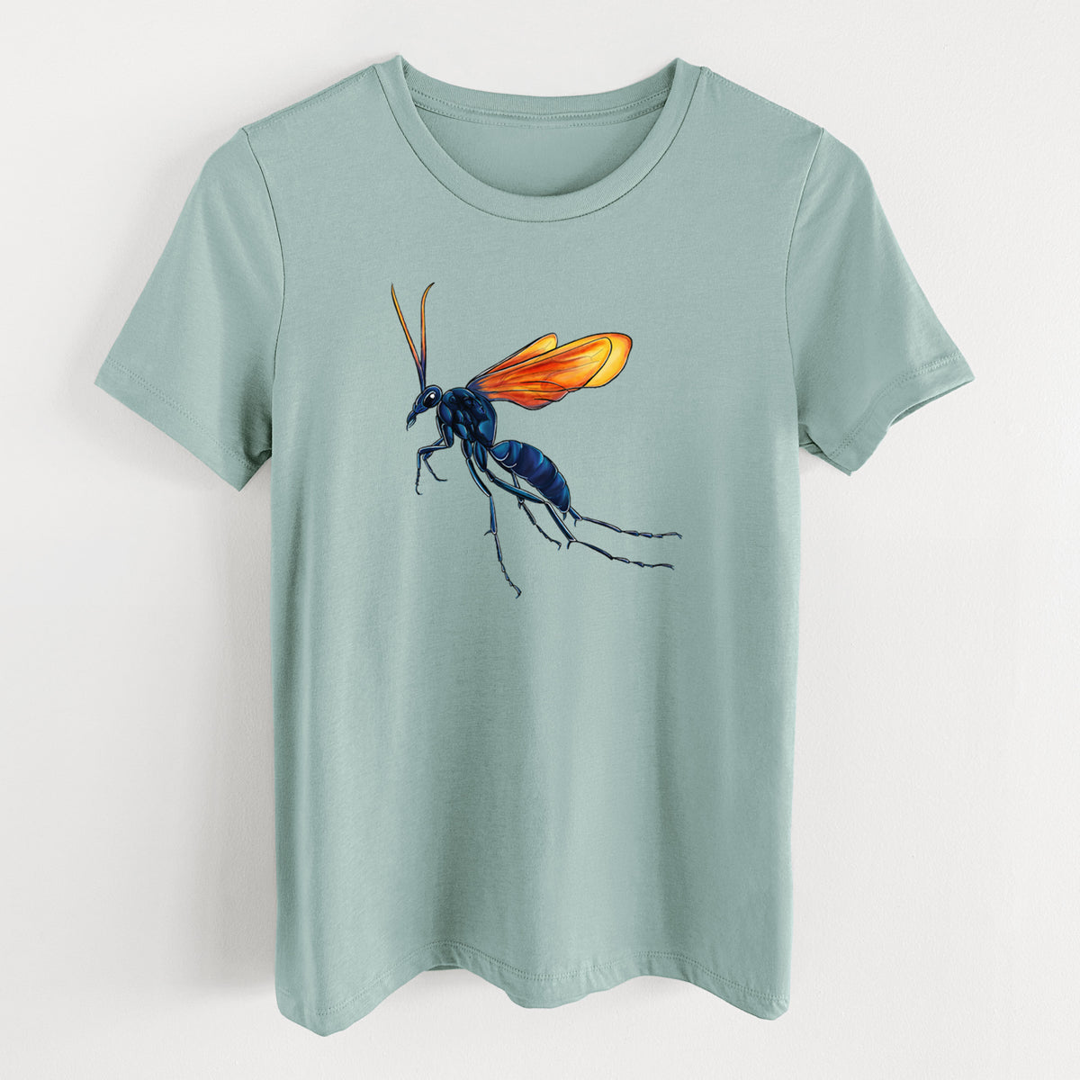 Dusty blue women's relaxed fit cotton t-shirt laid flat, printed with a full-color illustration of a tarantula hawk wasp with a blue body and orange wings.