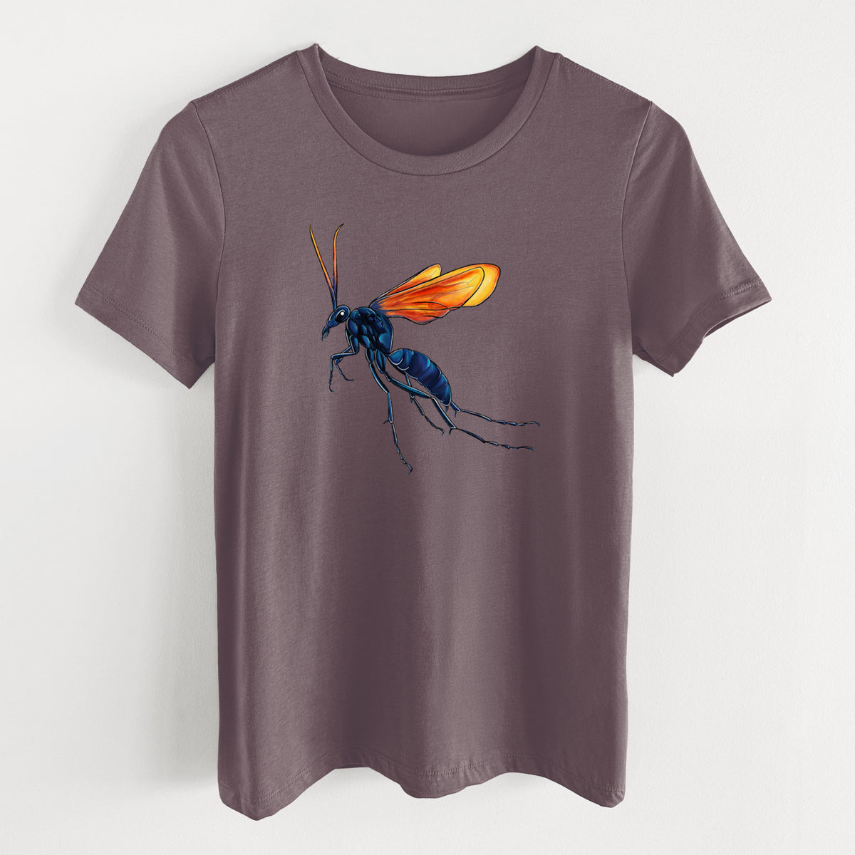 Purple storm women's relaxed fit cotton t-shirt laid flat, printed with a full-color illustration of a tarantula hawk wasp with a blue body and orange wings.
