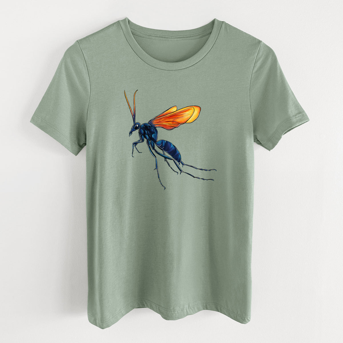 Sage green women's relaxed fit cotton t-shirt laid flat, printed with a full-color illustration of a tarantula hawk wasp with a blue body and orange wings.