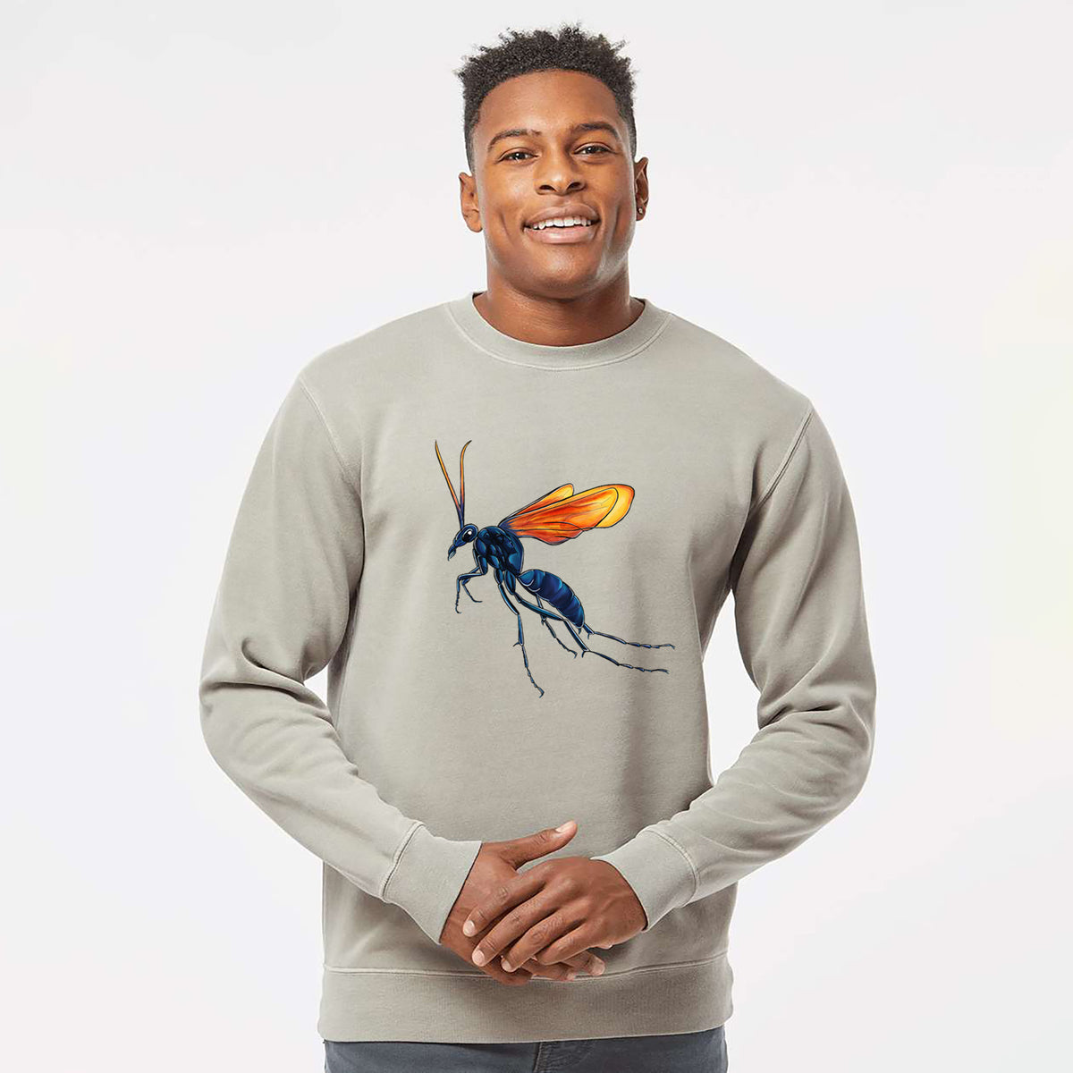 Model wearing a cement grey pigment dyed crewneck sweatshirt printed with a full-color illustration of a tarantula hawk wasp with a blue body and orange wings.