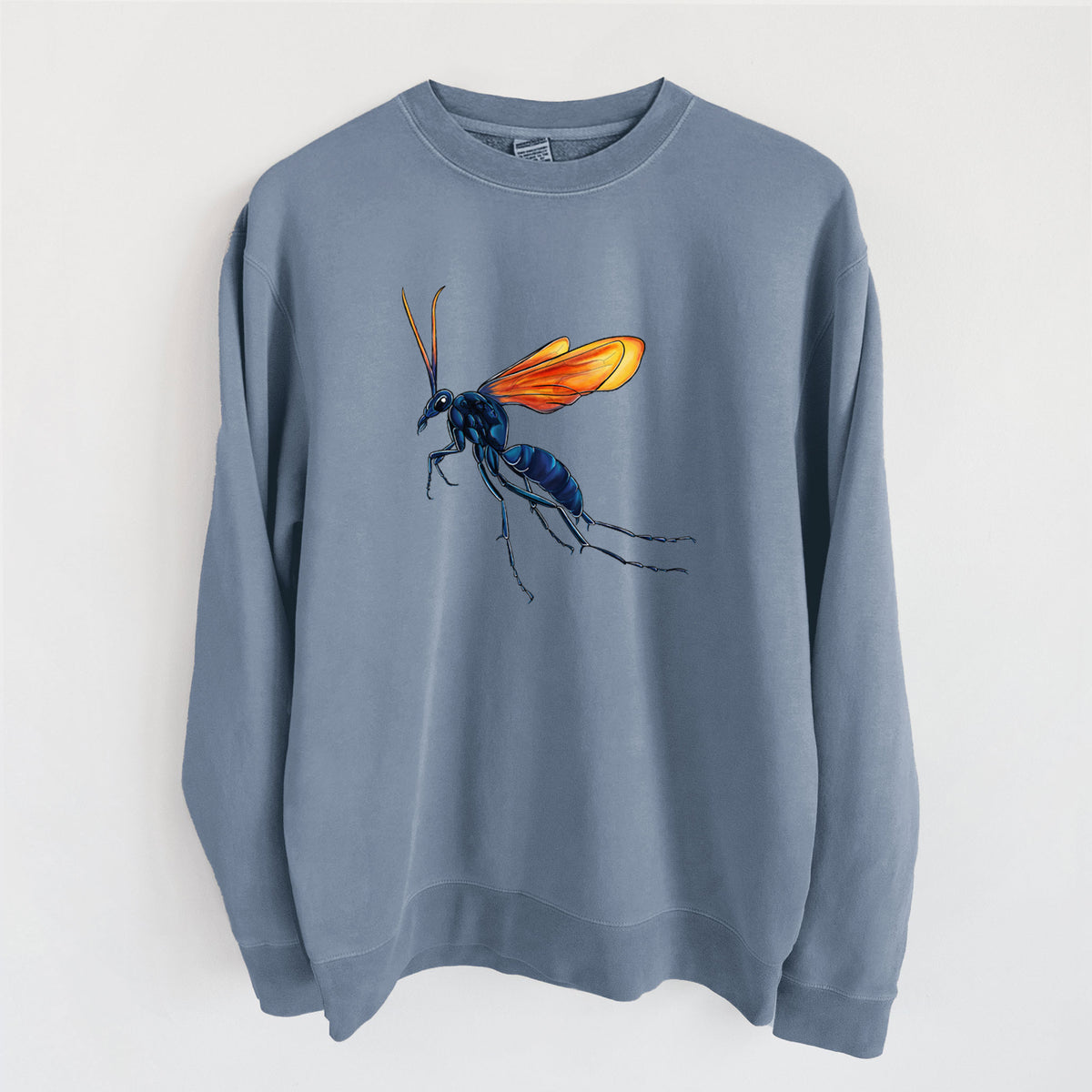 Slate blue pigment dyed crewneck sweatshirt laid flat, printed with a full-color illustration of a tarantula hawk wasp with a blue body and orange wings.