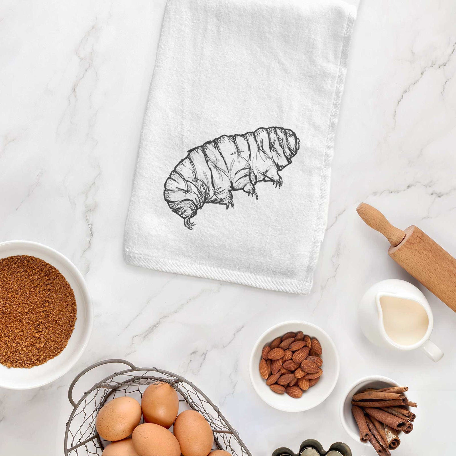 White hand towel printed with a detailed black ink illustration of a tardigrade, or water bear.