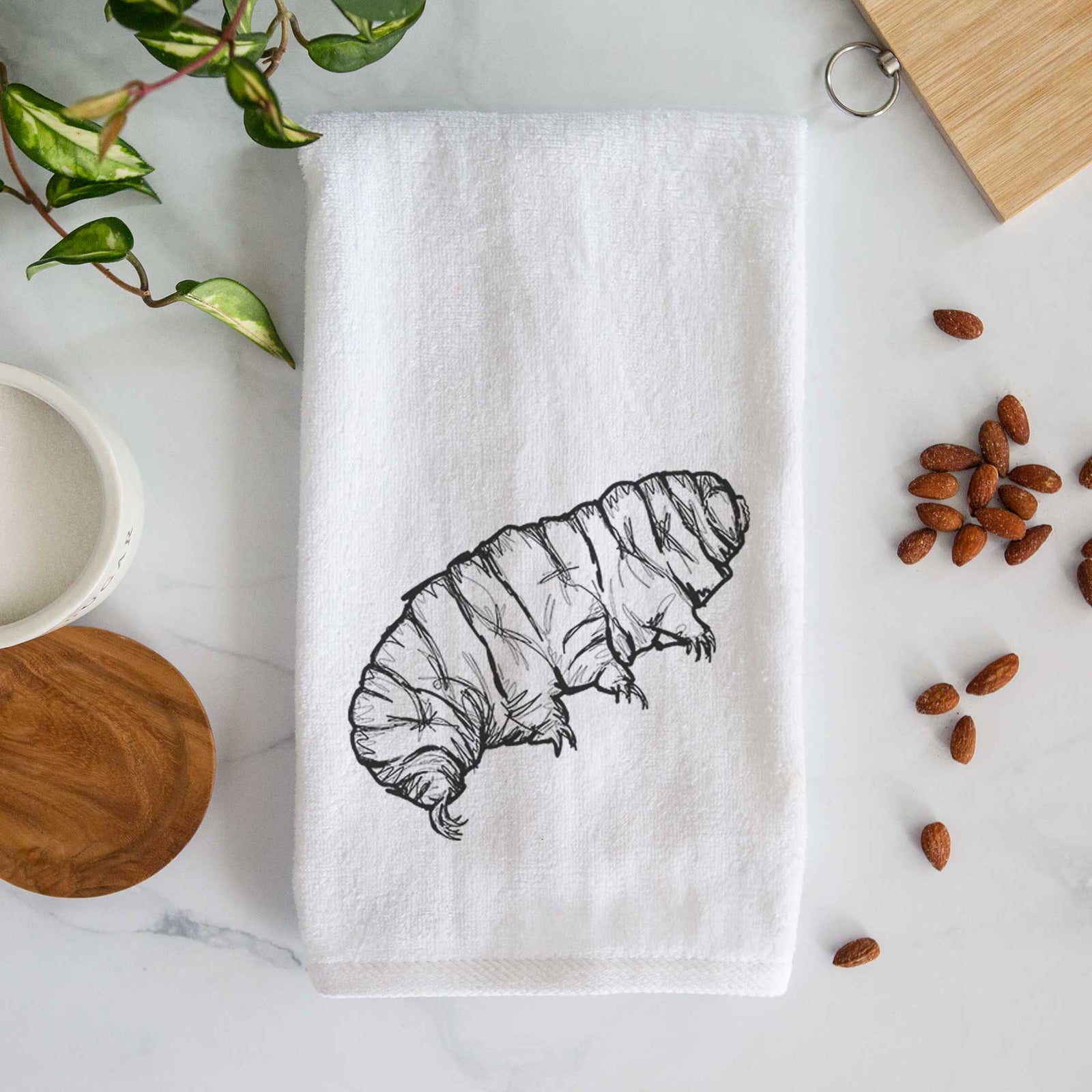 White hand towel printed with a detailed black ink illustration of a tardigrade, or water bear.