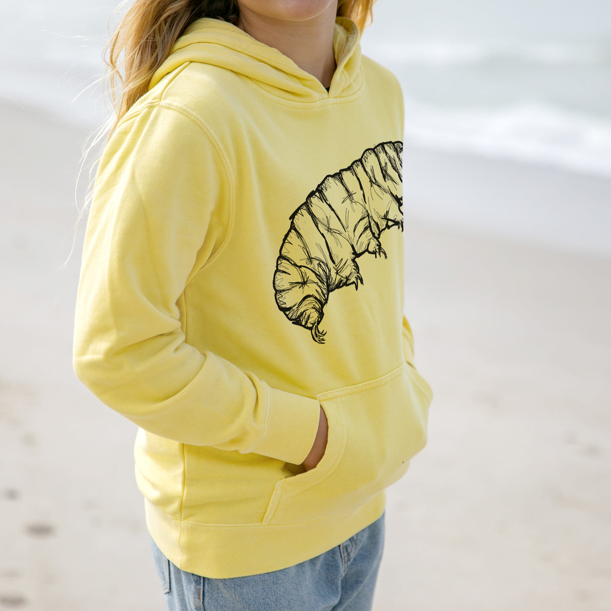 Girl wearing a youth pigment dyed hoodie printed with a detailed black ink illustration of a tardigrade, or water bear.