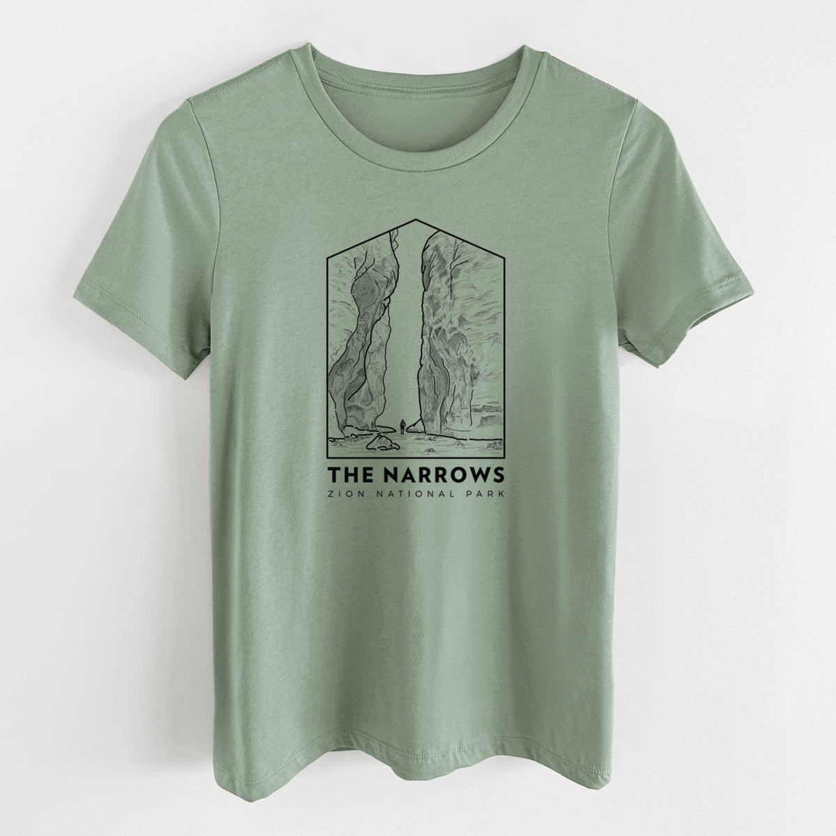 Sage green women's relaxed fit cotton t-shirt laid flat, printed with a black line art badge of the tall canyon walls of The Narrows, with the words The Narrows.