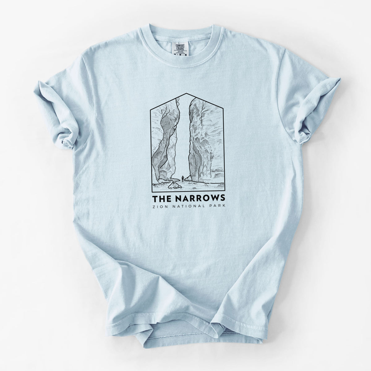 Chambray blue Comfort Colors t-shirt laid flat, printed with a black line art badge of the tall canyon walls of The Narrows, with the words The Narrows.