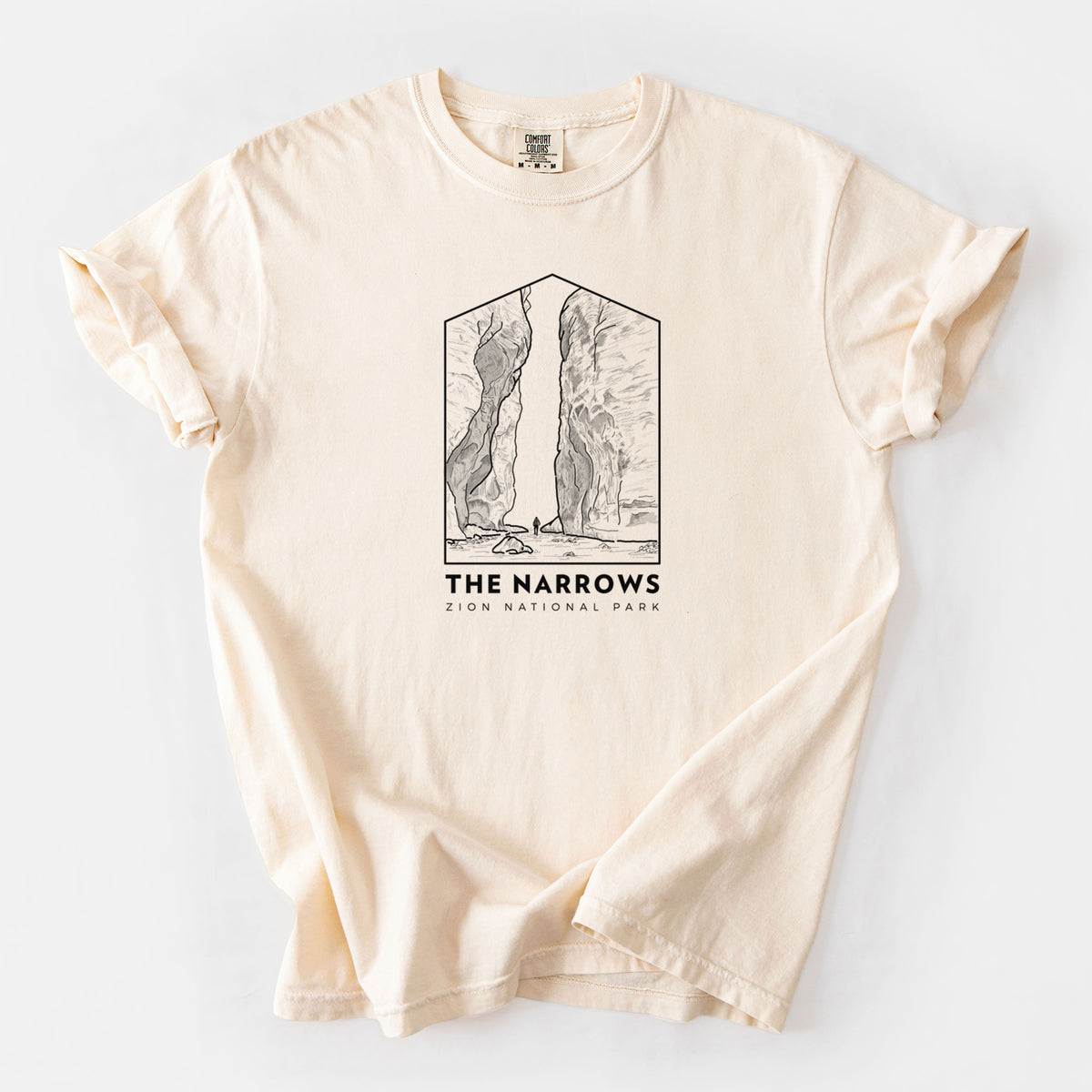 Ivory Comfort Colors t-shirt laid flat, printed with a black line art badge of the tall canyon walls of The Narrows, with the words The Narrows.