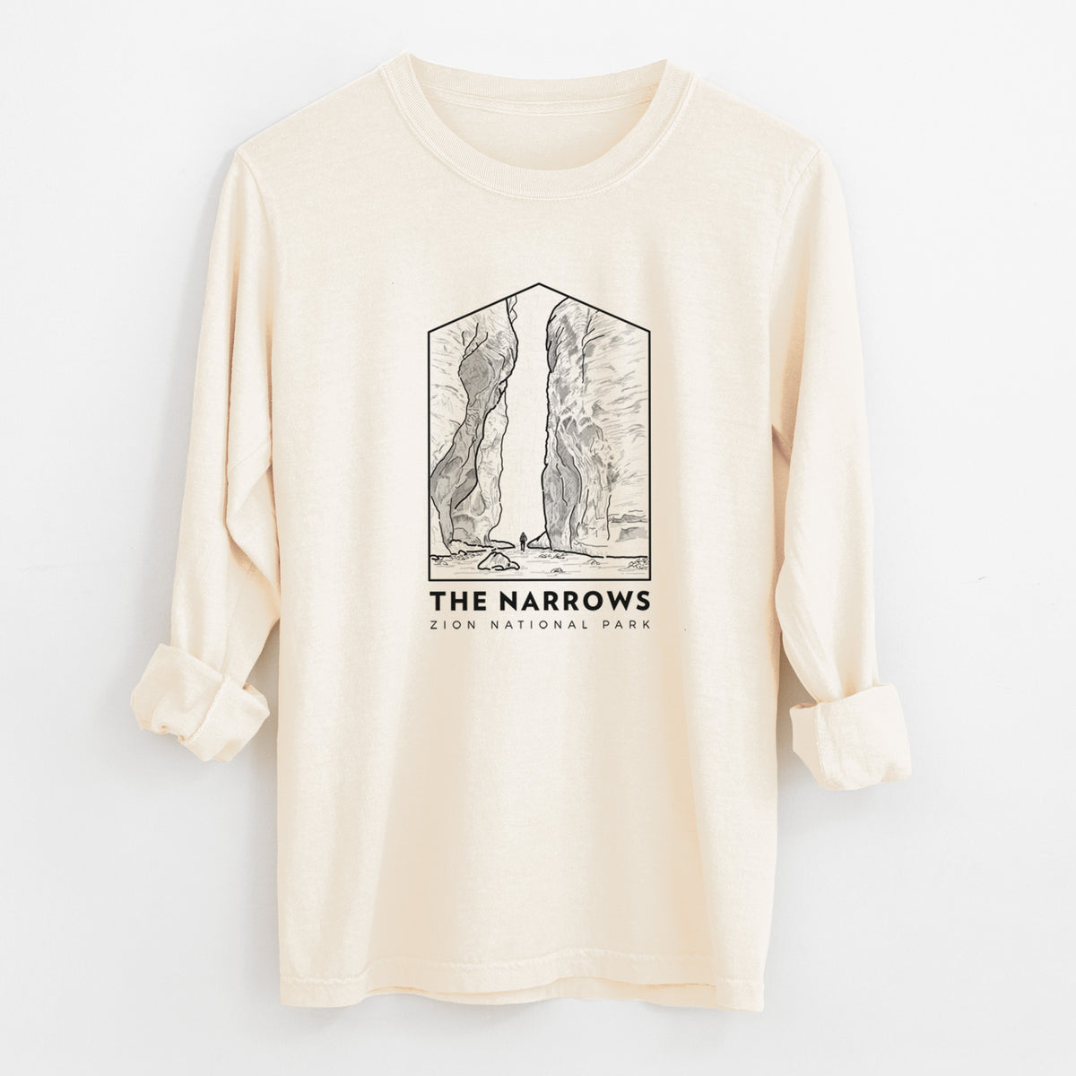 Ivory Comfort Colors long sleeve shirt laid flat with the cuffs rolled, printed with a black line art badge of the tall canyon walls of The Narrows, with the words The Narrows.