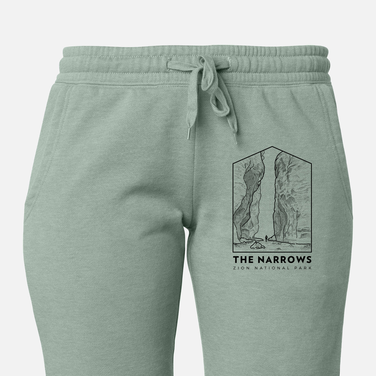 Front of sage green Cali Wave sweatpants, printed with a black line art badge of the tall canyon walls of The Narrows, with the words The Narrows on the leg.