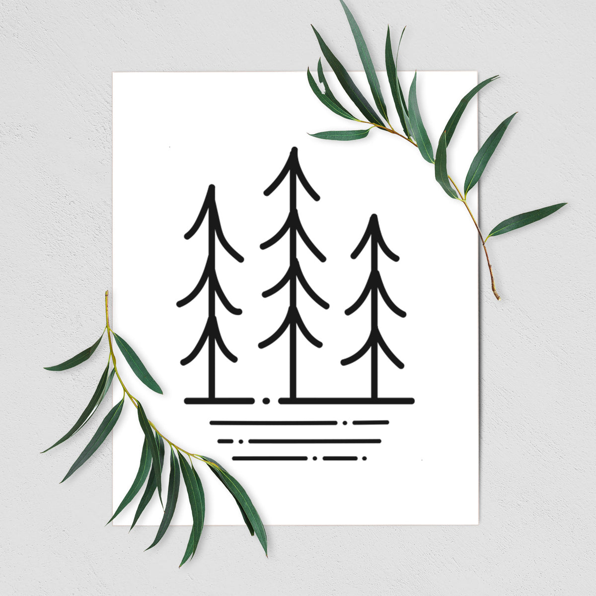 Art print of black line art of three simple pine trees above horizontal lines, shown with eucalyptus leaves.