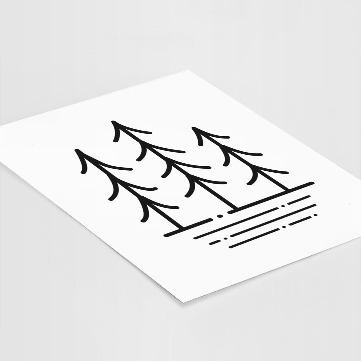 Art print of black line art of three simple pine trees above horizontal lines, lying at an angle on a white surface.