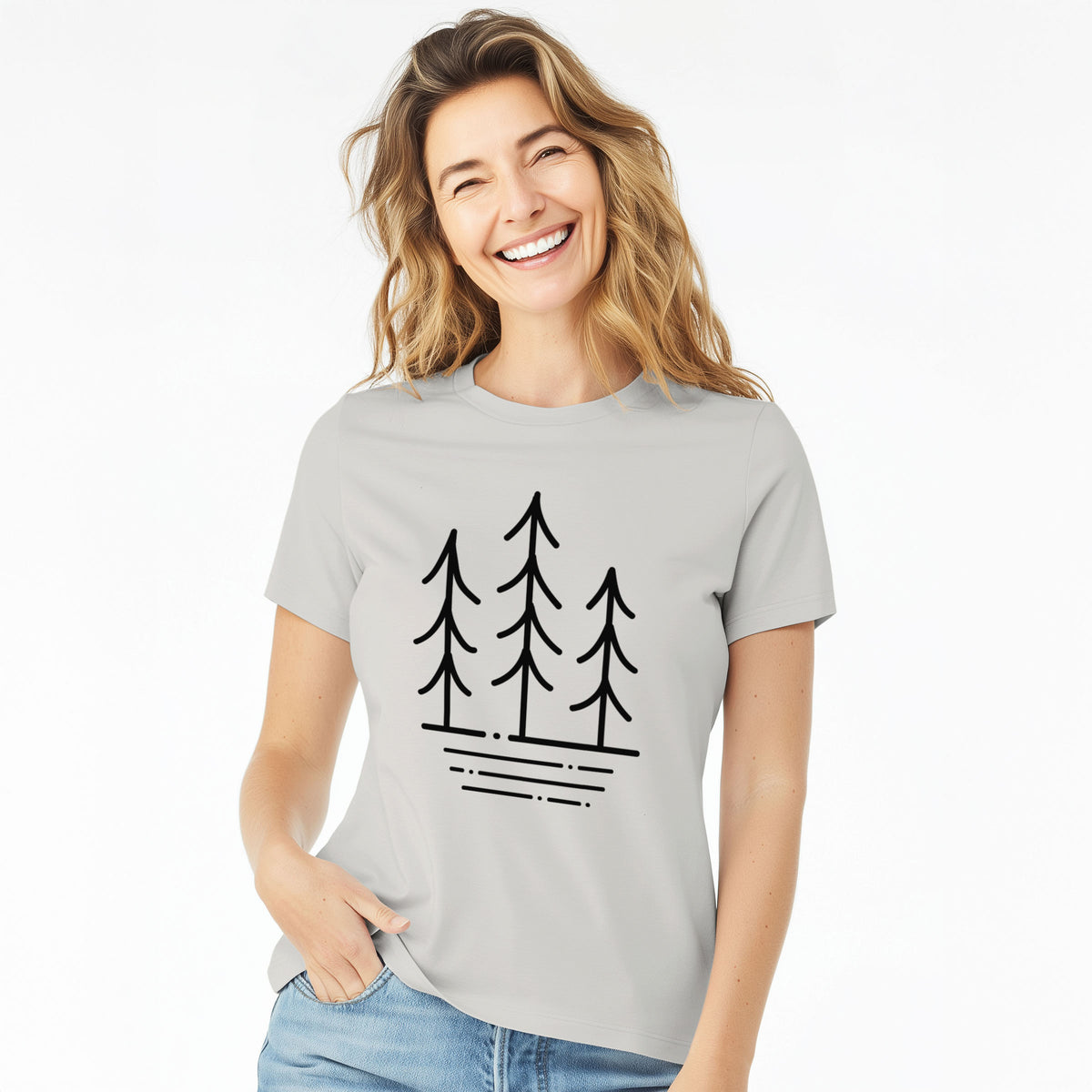 Woman wearing a lunar grey women's relaxed fit cotton t-shirt printed with black line art of three simple pine trees above horizontal lines.