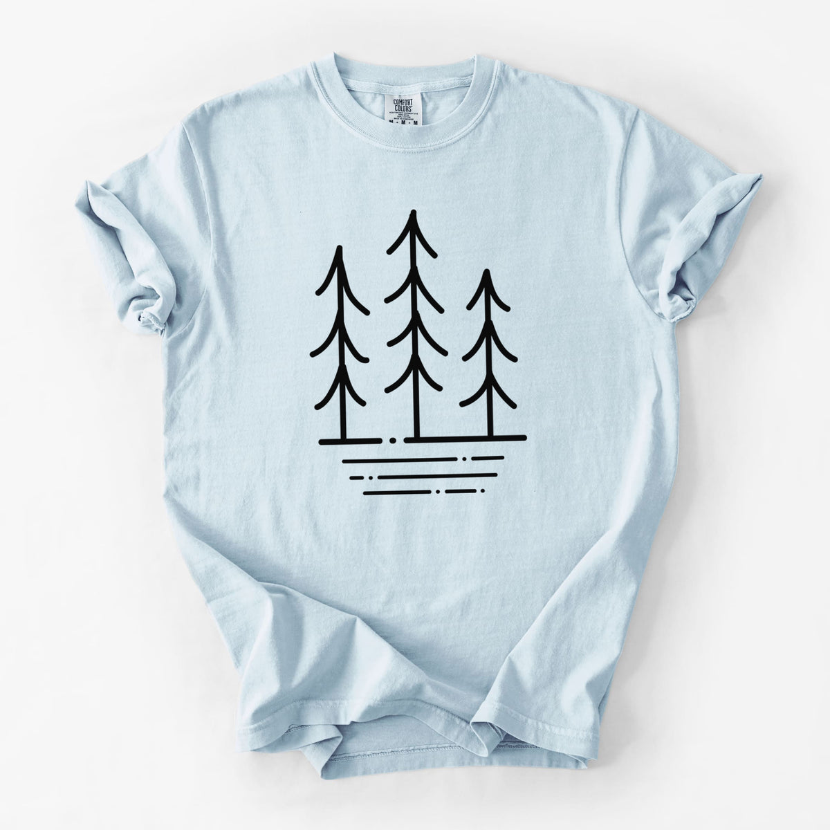 Chambray blue Comfort Colors t-shirt laid flat, printed with black line art of three simple pine trees above horizontal lines.