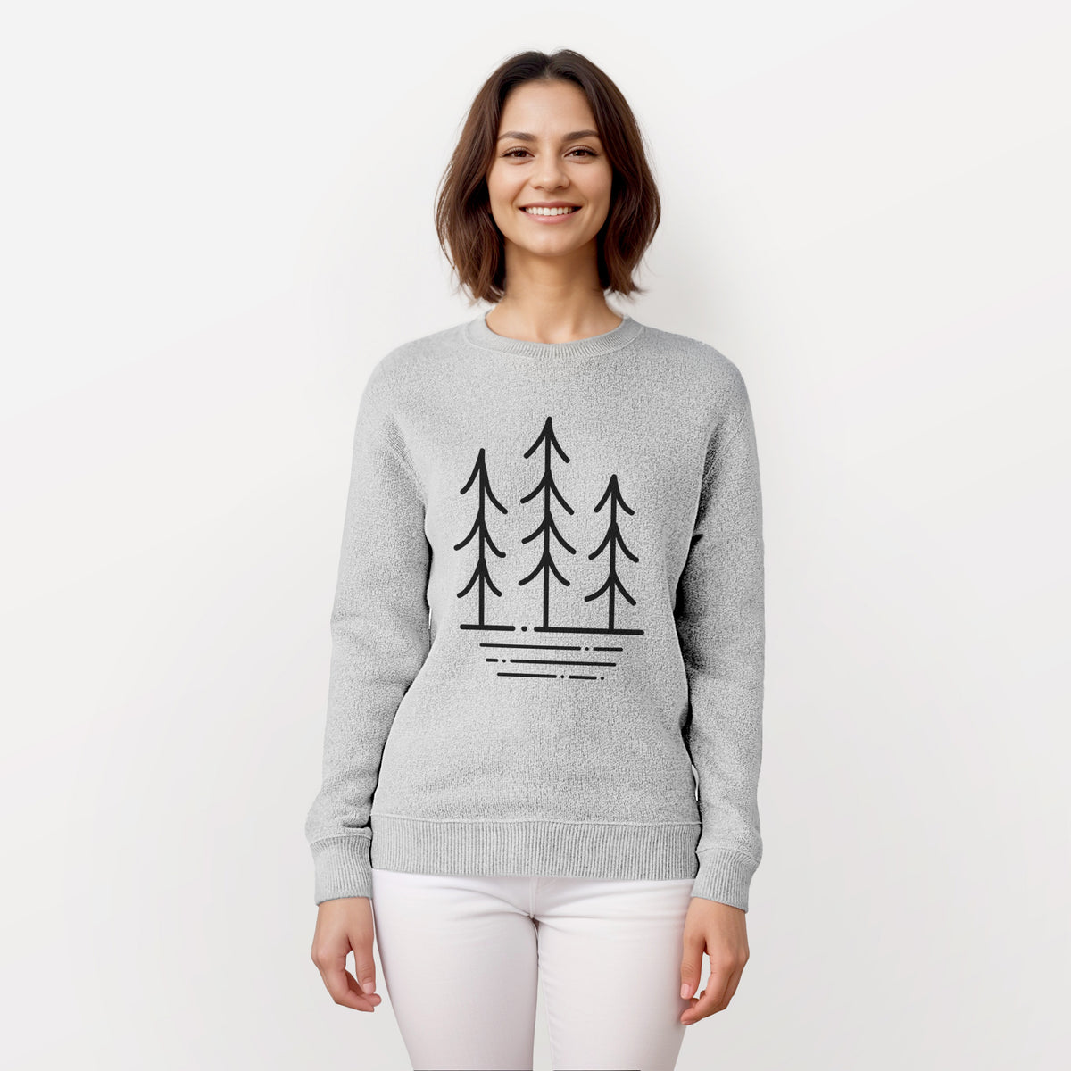 Woman wearing a knit sweatshirt printed with black line art of three simple pine trees above horizontal lines.