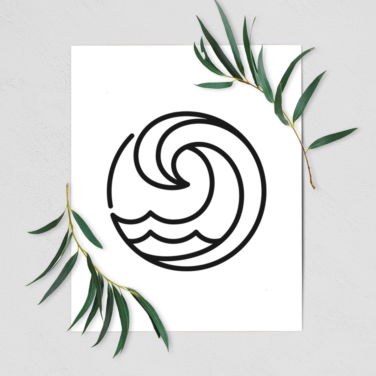 Art print of a bold black line art circle of a curling ocean wave, shown with eucalyptus leaves.