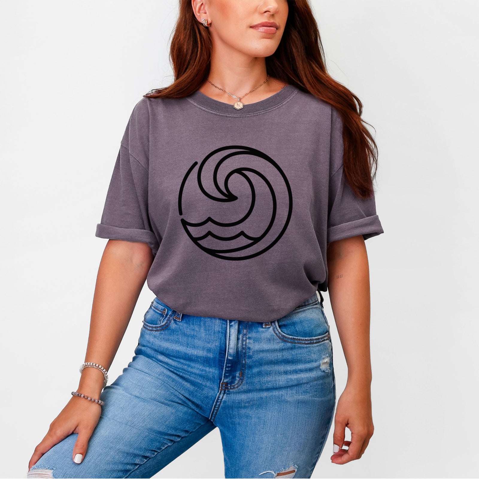 Blue jean Comfort Colors t-shirt laid flat, printed with a bold black line art circle of a curling ocean wave.