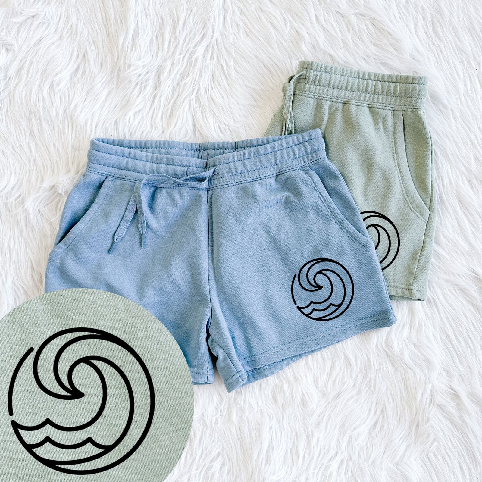 Two pairs of Cali Wave shorts in different colors printed with a bold black line art circle of a curling ocean wave, with a close-up of the print.