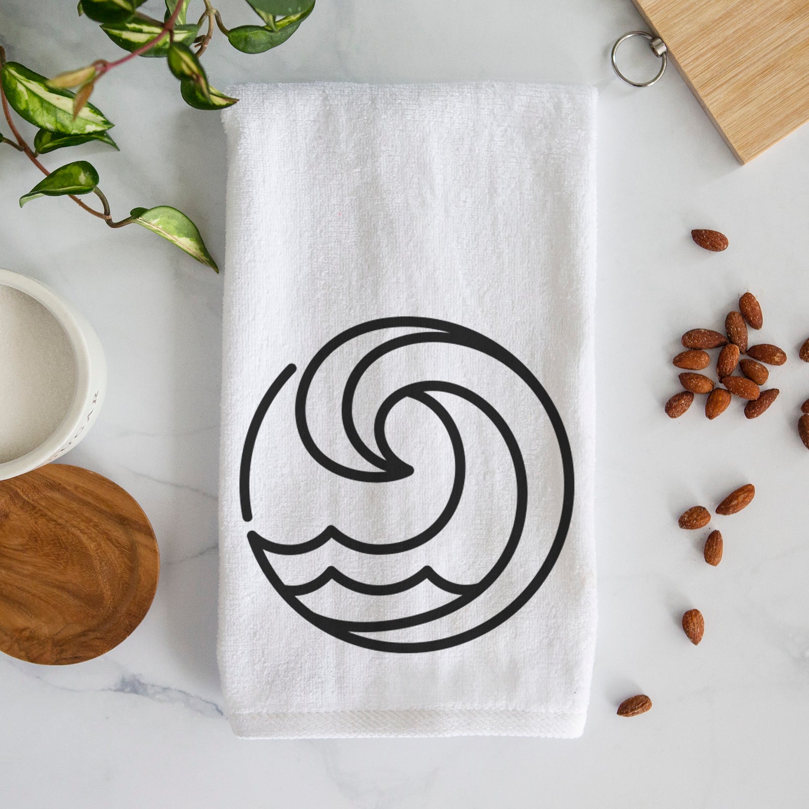 White hand towel printed with a bold black line art circle of a curling ocean wave.
