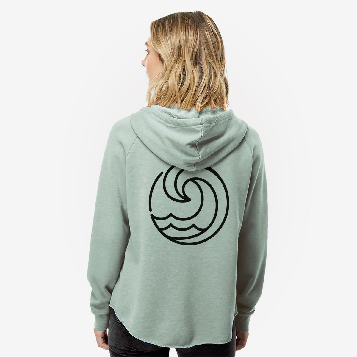 Woman wearing a sage green women's Cali Wave zip-up sweatshirt printed with a bold black line art circle of a curling ocean wave, seen from behind.