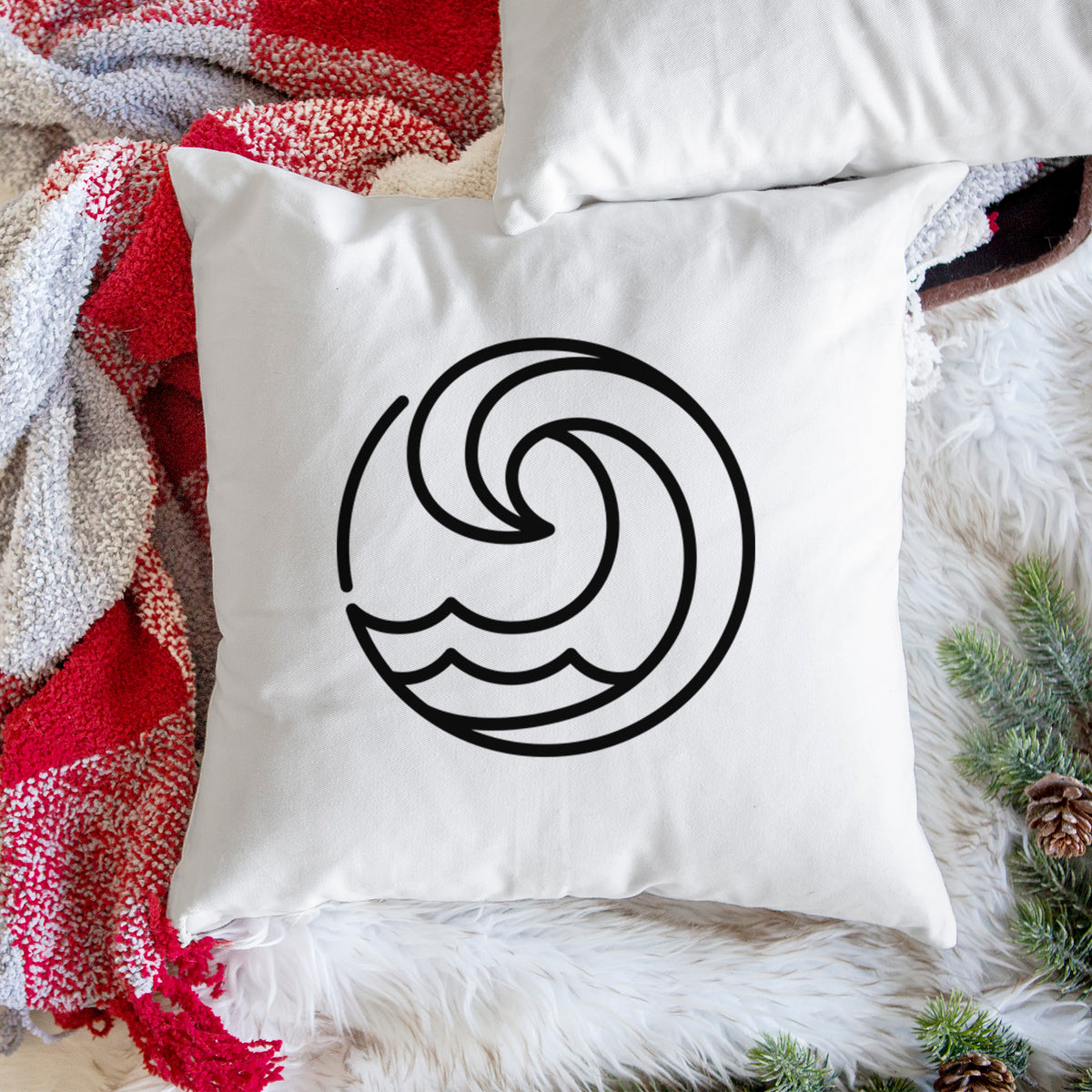 White pillow cover printed with a bold black line art circle of a curling ocean wave, on a woven chair.
