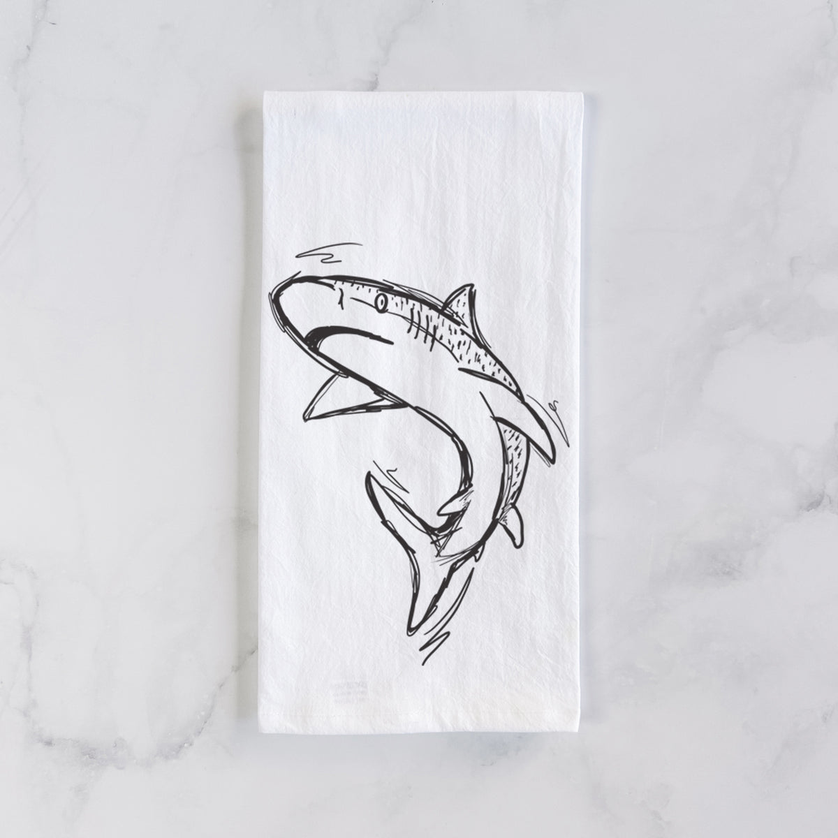 White cotton tea towel laid flat on marble, printed with a black ink illustration of a tiger shark swimming in a curve.