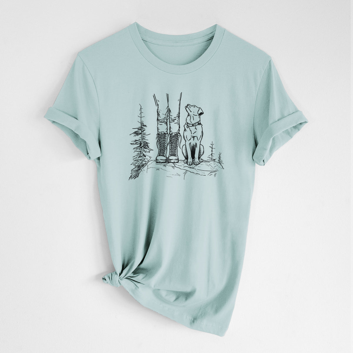 Dusty blue lightweight cotton t-shirt laid flat with the sleeves rolled, printed with a black ink illustration of a hiker in boots and a dog sitting side by side on a forest trail, seen from behind.