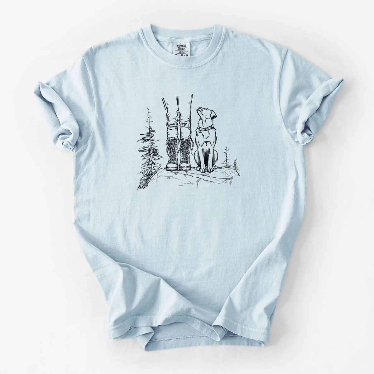 Chambray blue Comfort Colors t-shirt laid flat, printed with a black ink illustration of a hiker in boots and a dog sitting side by side on a forest trail, seen from behind.