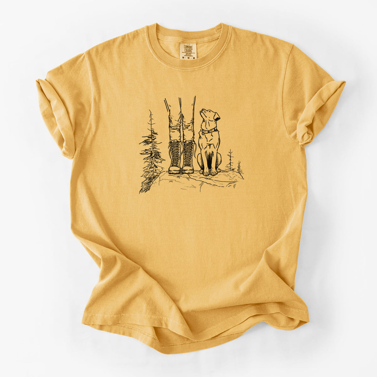 Golden wheat yellow Comfort Colors t-shirt laid flat, printed with a black ink illustration of a hiker in boots and a dog sitting side by side on a forest trail, seen from behind.