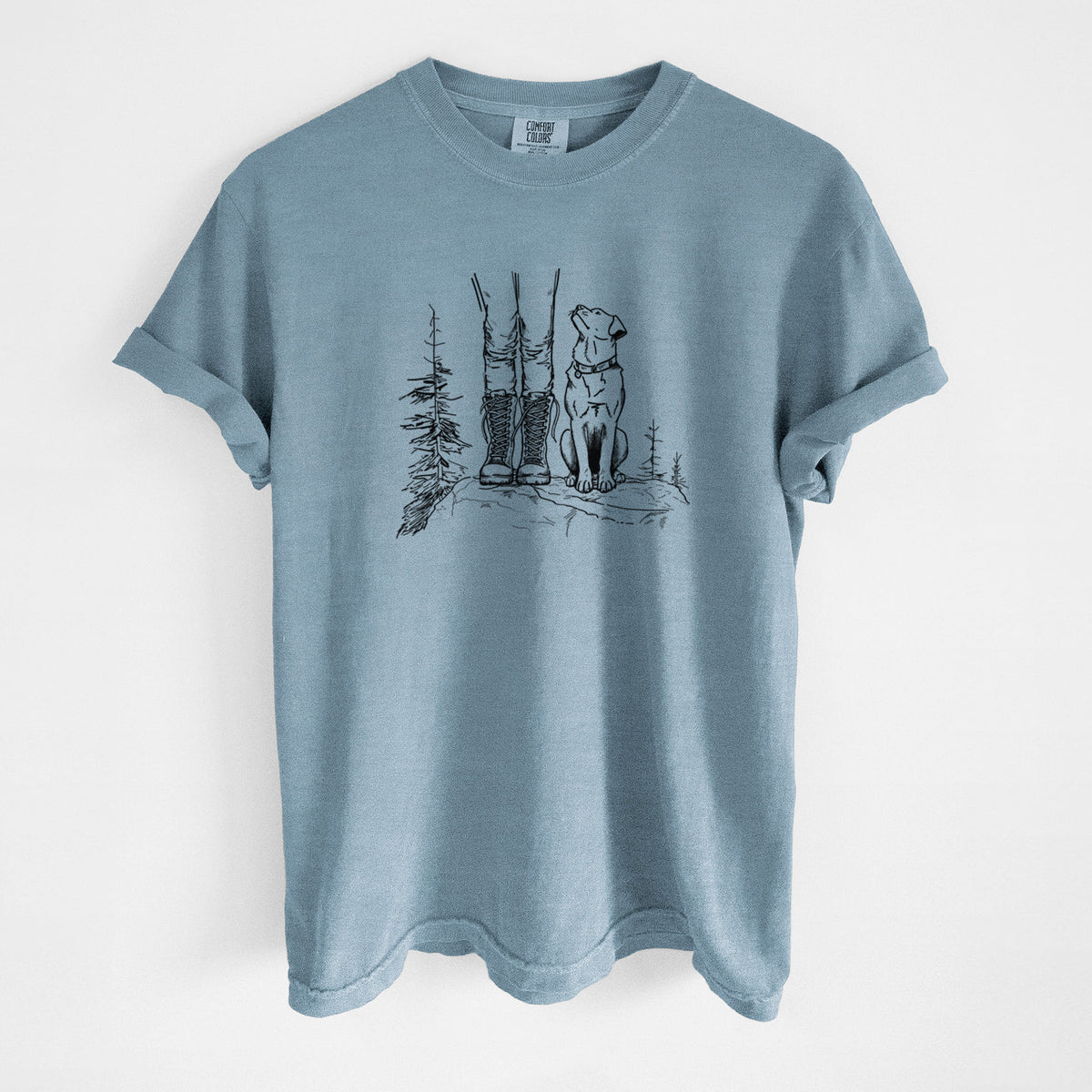 Steel blue Comfort Colors t-shirt laid flat, printed with a black ink illustration of a hiker in boots and a dog sitting side by side on a forest trail, seen from behind.