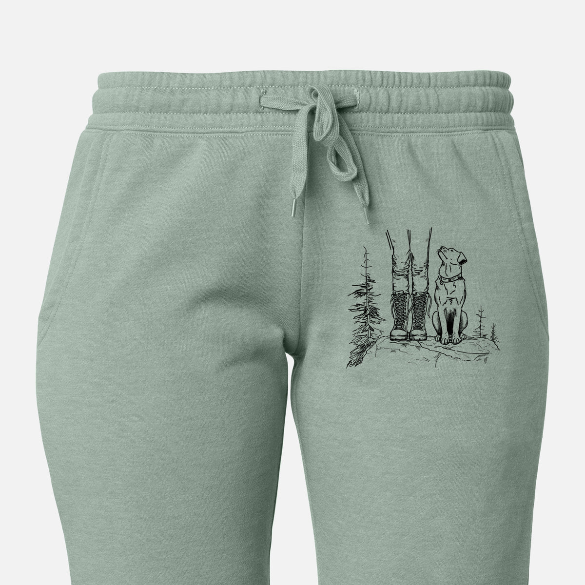 Front of sage green Cali Wave sweatpants, printed with a black ink illustration of a hiker in boots and a dog sitting side by side on a forest trail, seen from behind on the leg.