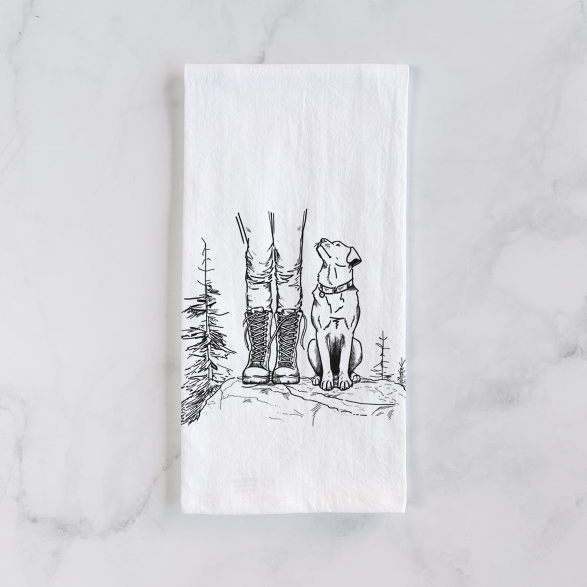 White cotton tea towel laid flat on marble, printed with a black ink illustration of a hiker in boots and a dog sitting side by side on a forest trail, seen from behind.