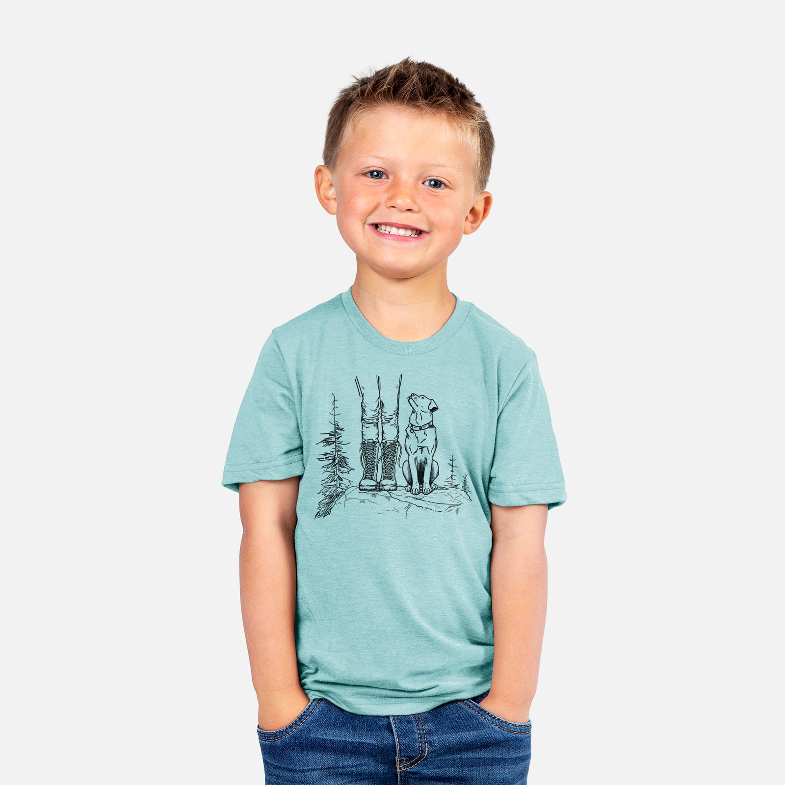 Two youth t-shirts in different colors on hangers, printed with a black ink illustration of a hiker in boots and a dog sitting side by side on a forest trail, seen from behind.