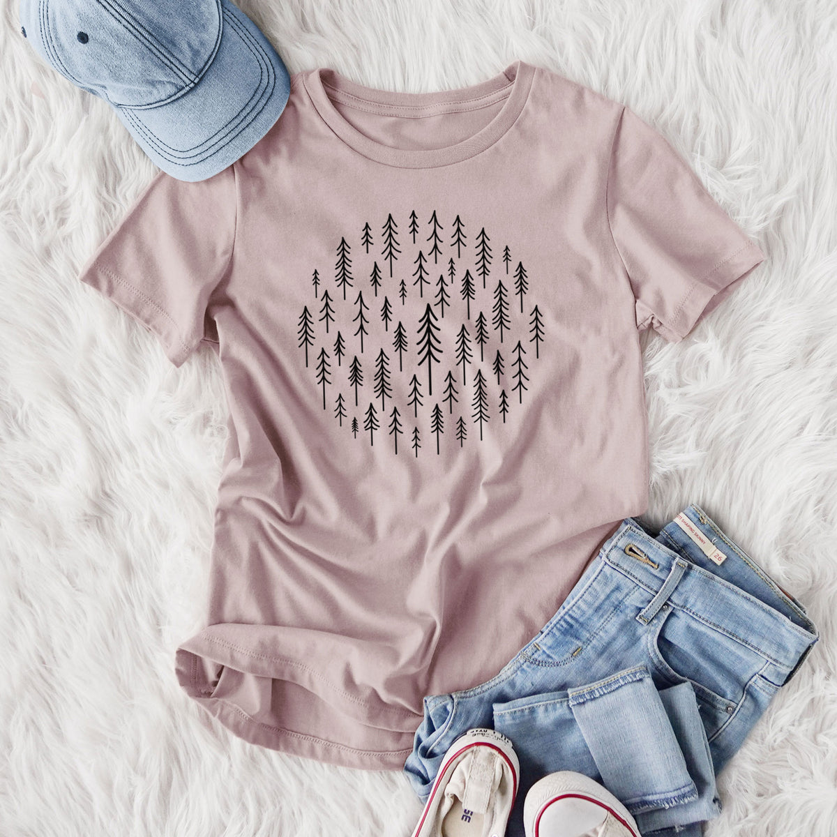 Women's relaxed fit cotton t-shirt printed with a circle made of small black ink pine trees, styled flat on a white faux fur rug with jeans.