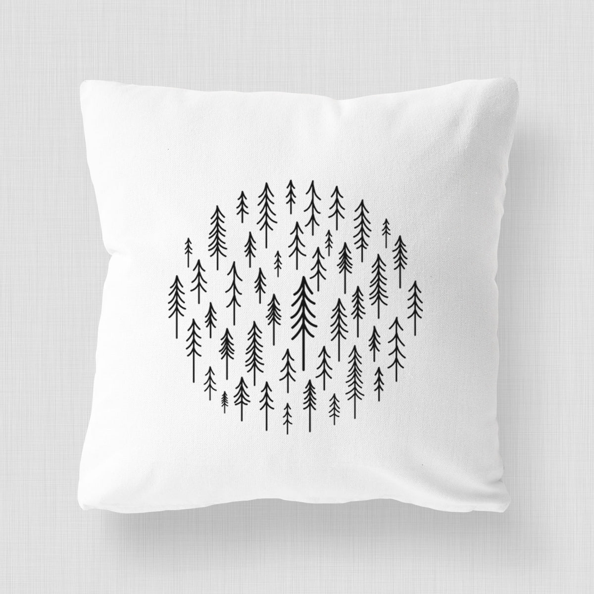 White pillow cover printed with a circle made of small black ink pine trees.