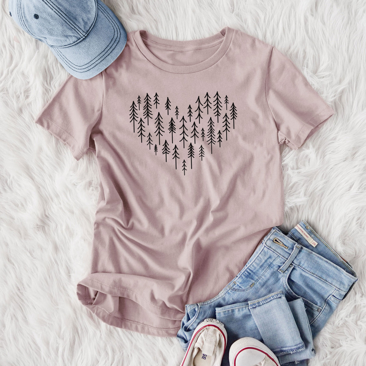 Women's relaxed fit cotton t-shirt printed with a heart shape made of small black ink pine trees, styled flat on a white faux fur rug with jeans.
