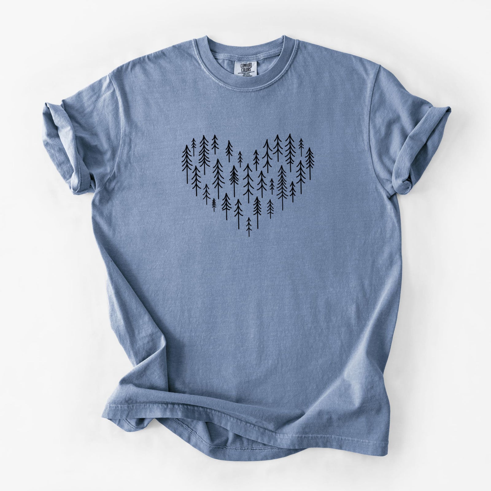 Blue jean Comfort Colors t-shirt laid flat, printed with a heart shape made of small black ink pine trees.