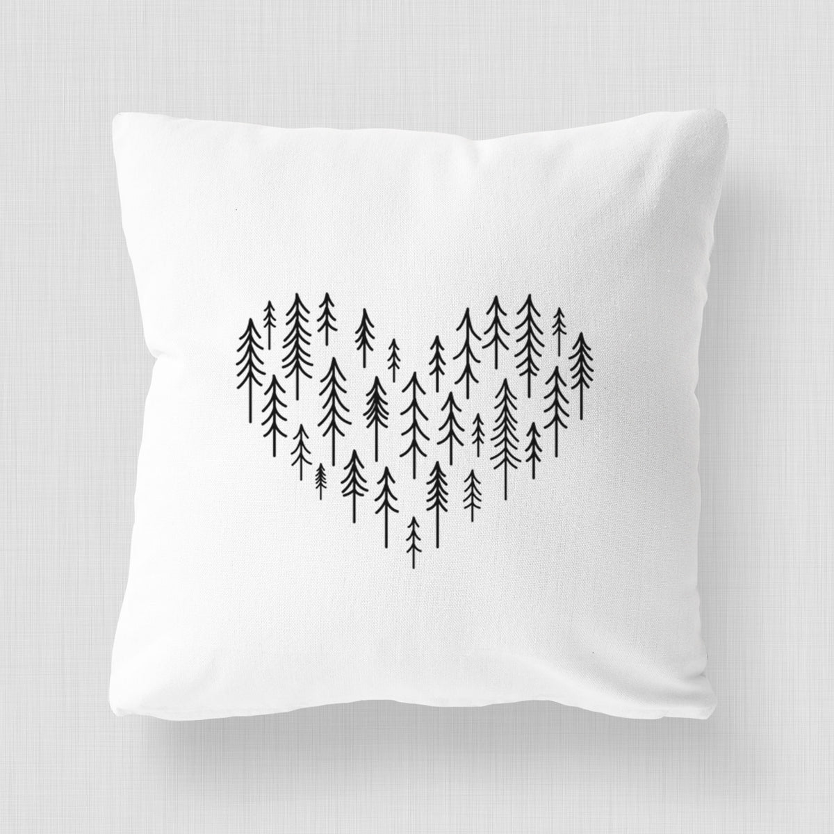 White pillow cover printed with a heart shape made of small black ink pine trees.