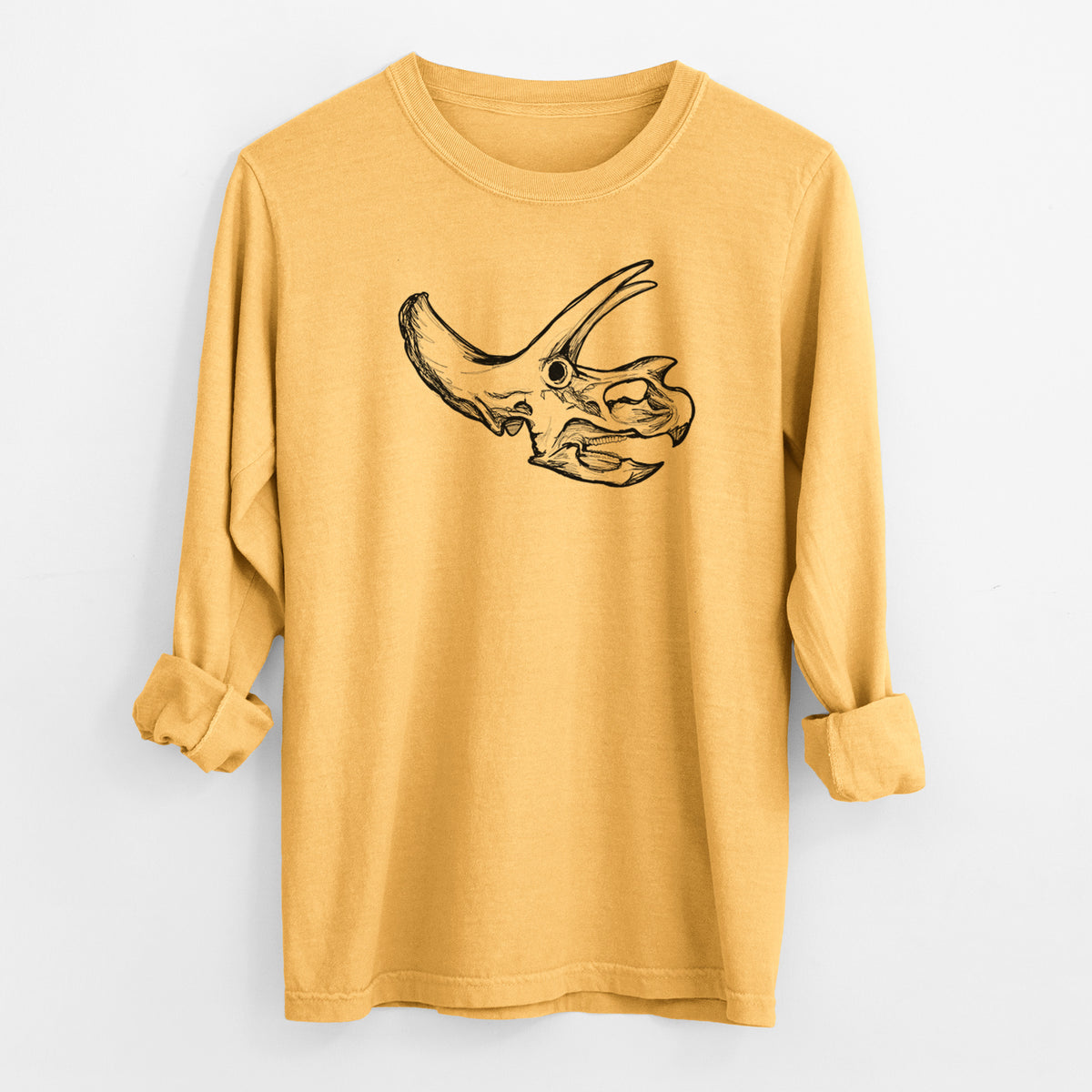 Golden wheat yellow Comfort Colors long sleeve shirt laid flat with the cuffs rolled, printed with a detailed black ink illustration of a Triceratops skull with its horns and frill.