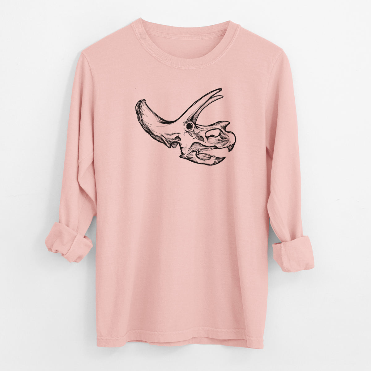 Peachy Comfort Colors long sleeve shirt laid flat with the cuffs rolled, printed with a detailed black ink illustration of a Triceratops skull with its horns and frill.