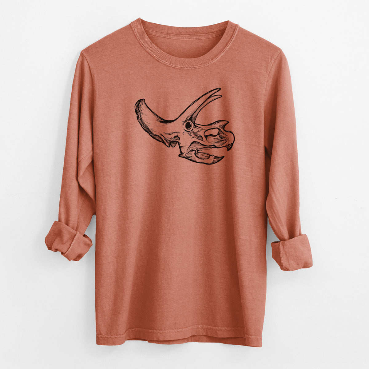 Yam burnt orange Comfort Colors long sleeve shirt laid flat with the cuffs rolled, printed with a detailed black ink illustration of a Triceratops skull with its horns and frill.
