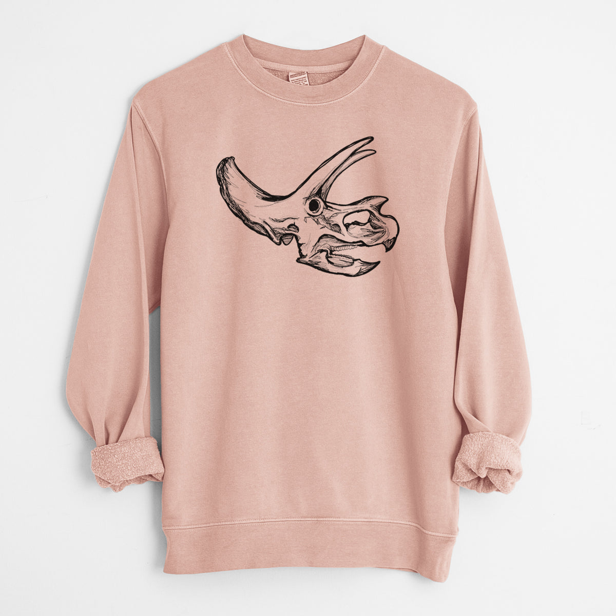Dusty pink pigment dyed crewneck sweatshirt laid flat with the sleeves rolled, printed with a detailed black ink illustration of a Triceratops skull with its horns and frill.