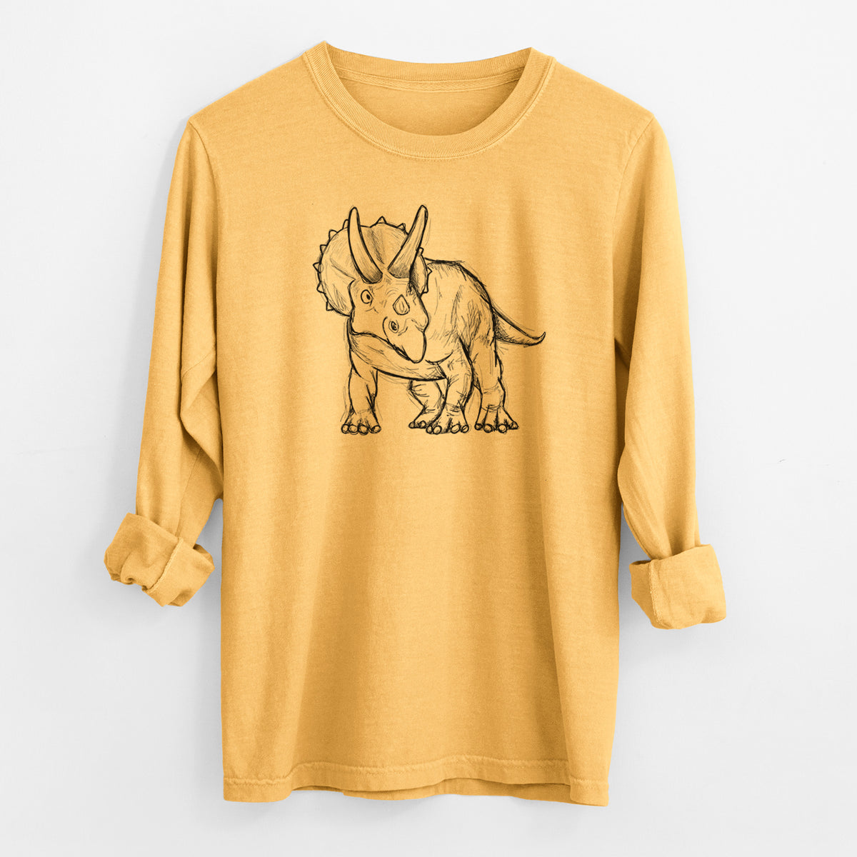 Golden wheat yellow Comfort Colors long sleeve shirt laid flat with the cuffs rolled, printed with a black ink illustration of a Triceratops walking.