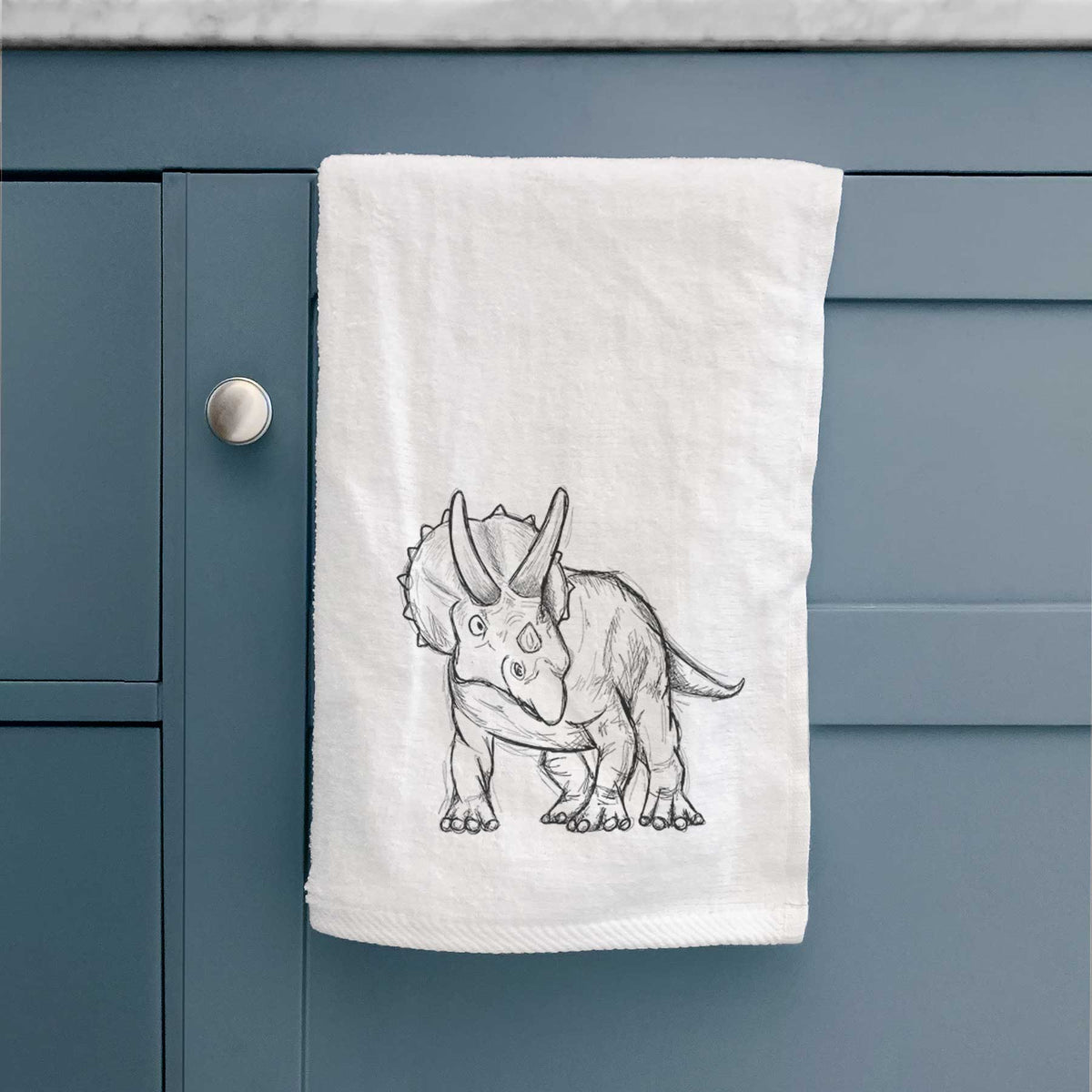 White hand towel printed with a black ink illustration of a Triceratops walking.