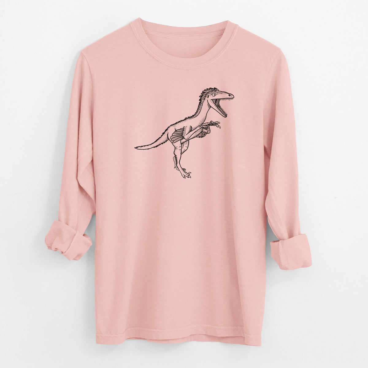 Peachy Comfort Colors long sleeve shirt laid flat with the cuffs rolled, printed with a black ink illustration of a Troodon dinosaur running.