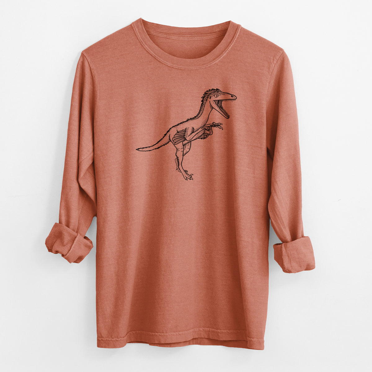 Yam burnt orange Comfort Colors long sleeve shirt laid flat with the cuffs rolled, printed with a black ink illustration of a Troodon dinosaur running.