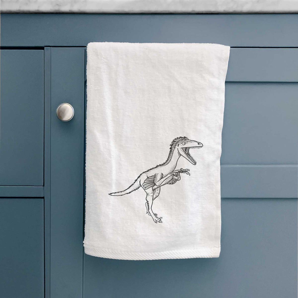 White hand towel printed with a black ink illustration of a Troodon dinosaur running.