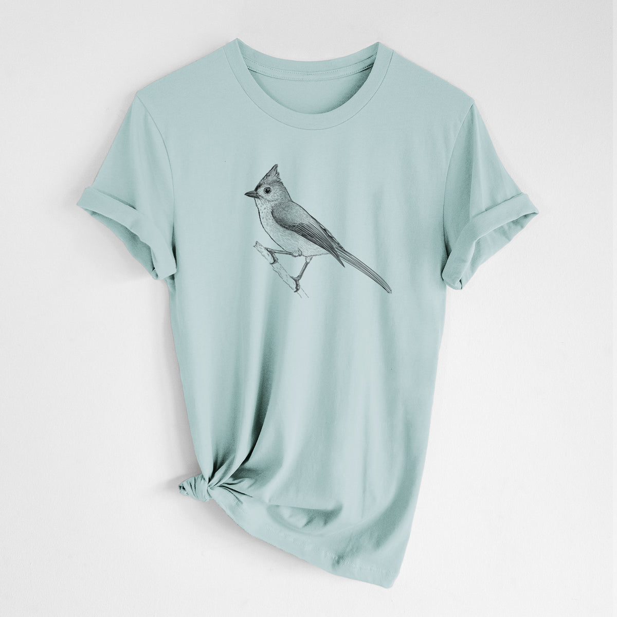 Dusty blue lightweight cotton t-shirt laid flat with the sleeves rolled, printed with a detailed black ink sketch of a tufted titmouse perched on a branch.