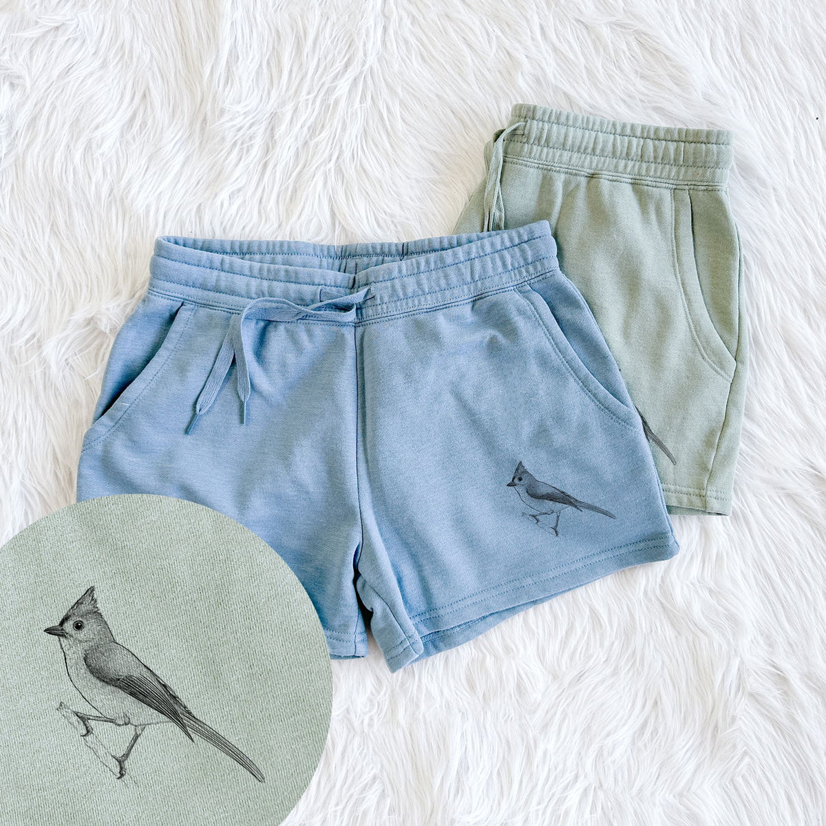 Two pairs of Cali Wave shorts in different colors printed with a detailed black ink sketch of a tufted titmouse perched on a branch, with a close-up of the print.